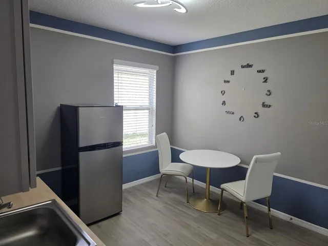 a view of a room with furniture a refrigerator and wooden floor