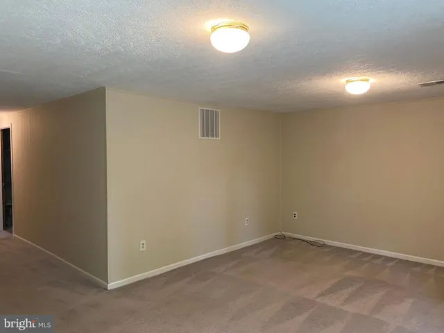 an empty room with a fan & a window