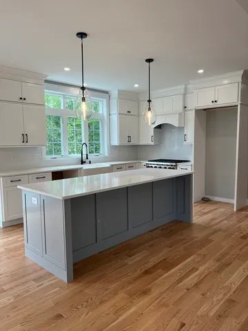 a kitchen with stainless steel appliances granite countertop a sink a stove and a wooden floors