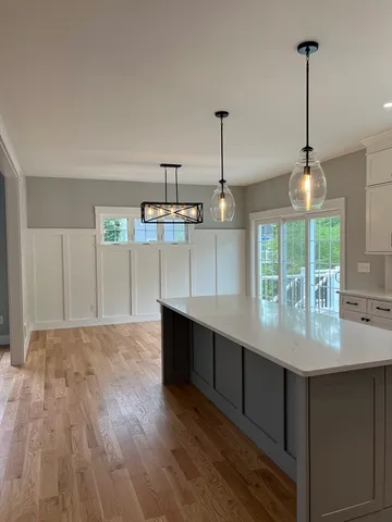 a kitchen with kitchen island stainless steel appliances a chandelier and wooden floor