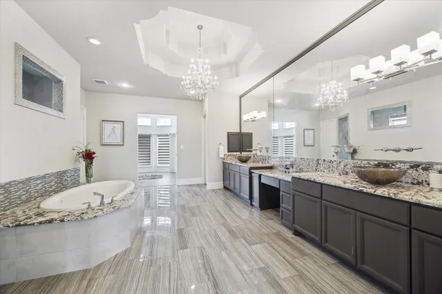 a spacious bathroom with a granite countertop sink a large mirror and a wooden floor