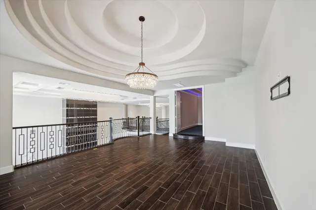 a view of an empty room with wooden floor kitchen view and a window