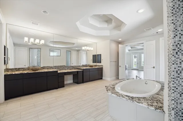 a large bathroom with a granite countertop double vanity sink a mirror and a bathtub