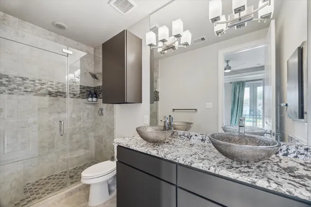 a bathroom with a granite countertop sink a toilet and a shower