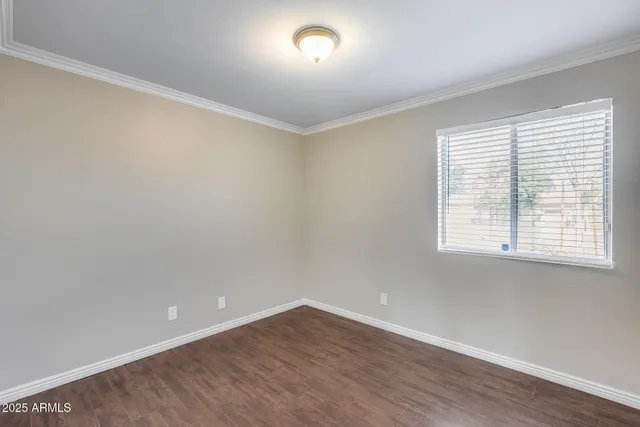 an empty room with wooden floor chandelier fan and windows