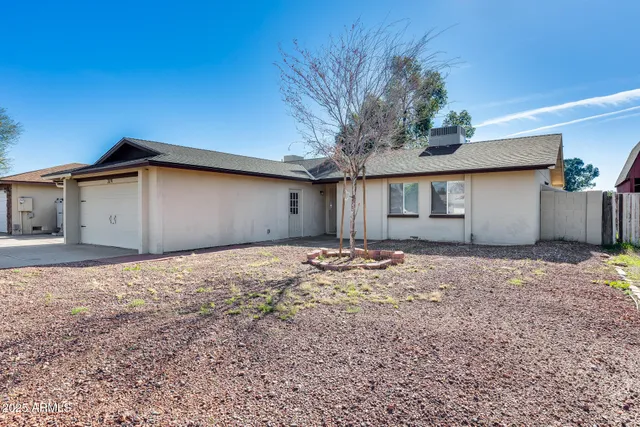 a view of a house with a yard and large tree