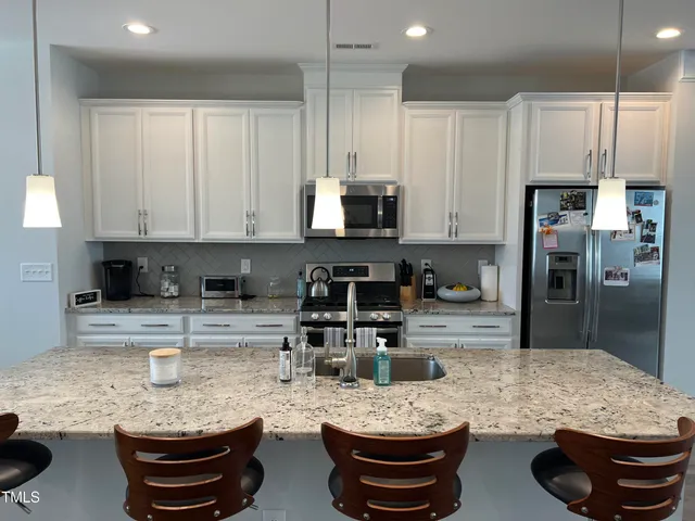 a kitchen with stainless steel appliances kitchen island granite countertop a stove refrigerator and cabinets