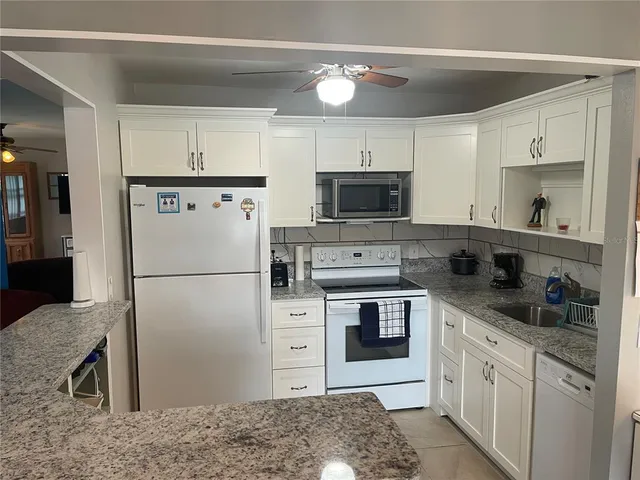 a kitchen with stainless steel appliances granite countertop a refrigerator a stove and a sink