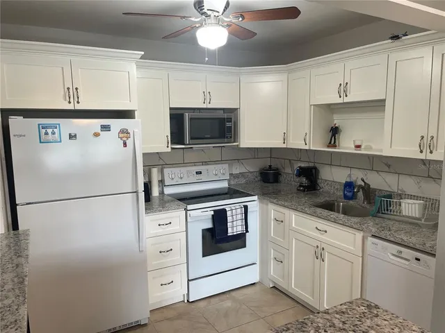 a white kitchen with cabinets stainless steel appliances and a counter space