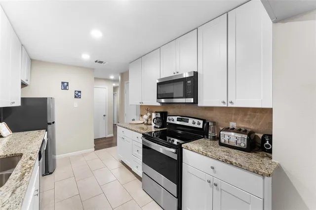 a kitchen with granite countertop white cabinets and stainless steel appliances