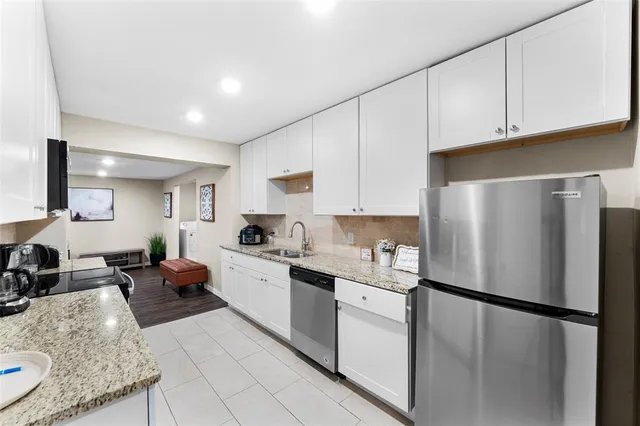 a kitchen with stainless steel appliances granite countertop a refrigerator sink stove and white cabinets