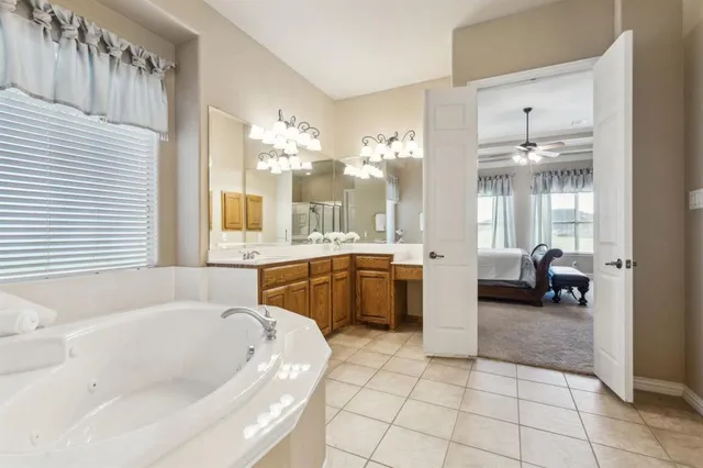 a bathroom with a tub a double vanity sink and mirror