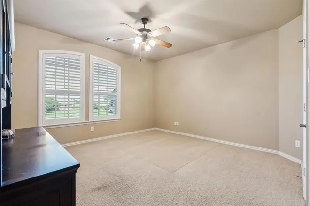 an empty room with windows and chandelier fan