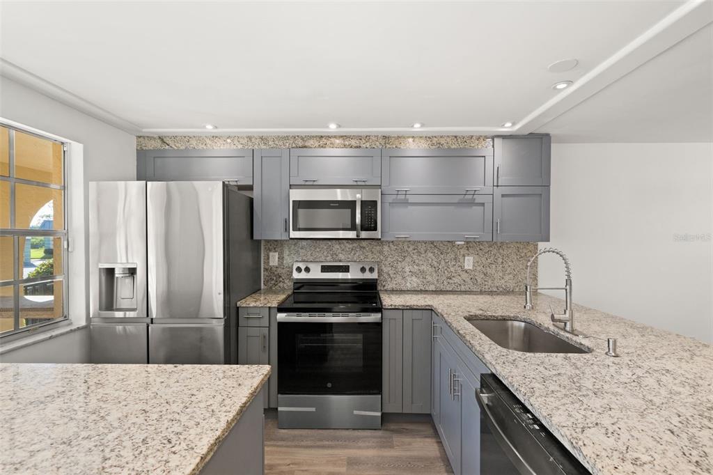 4127 Stratford Drive, Unit 4127 New Port Richey, FL 34652 - Photo 9 of 45 a kitchen with granite countertop a sink stove and refrigerator