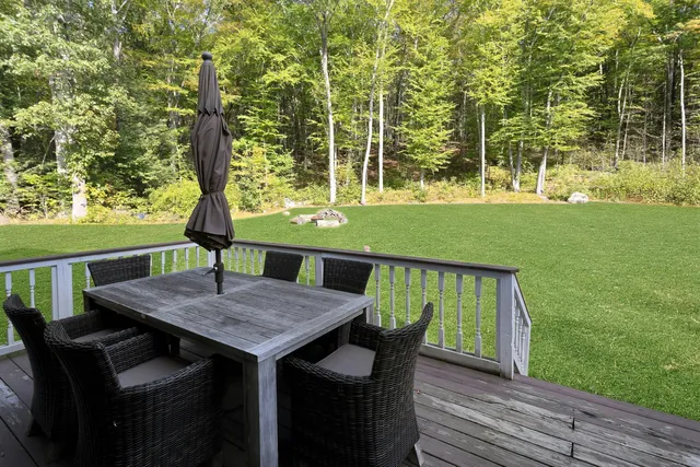 a view of a patio with table and chairs with wooden floor and fence