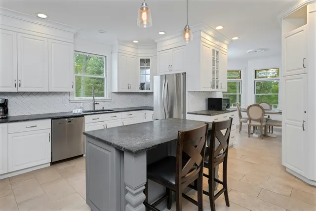 a kitchen with stainless steel appliances granite countertop a table chairs sink refrigerator and microwave