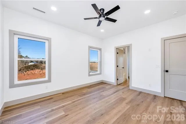 a view of a big room with wooden floor and windows