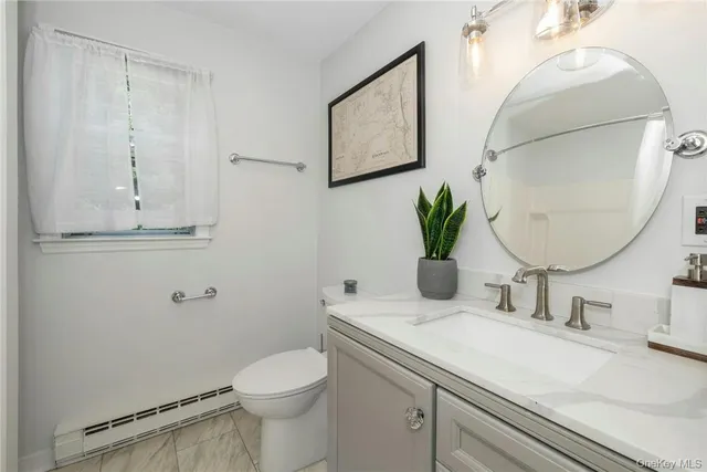 a bathroom with a granite countertop toilet sink and mirror