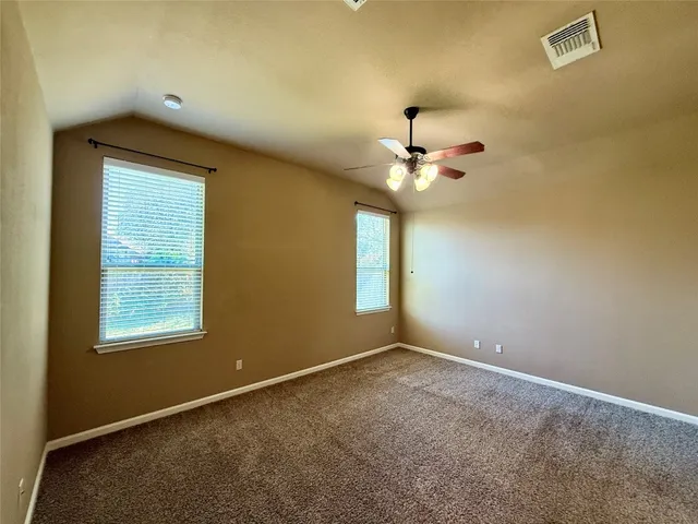 an empty room with a chandelier fan and windows