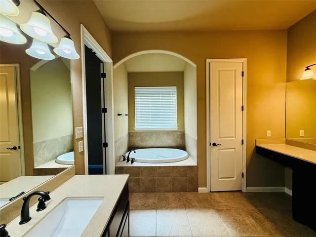 a bathroom with a tub a sink and a large mirror
