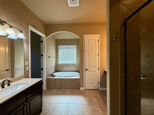 a spacious bathroom with a tub sink and mirror