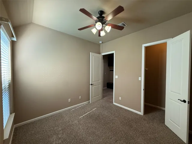 an empty room with a chandelier fan and windows