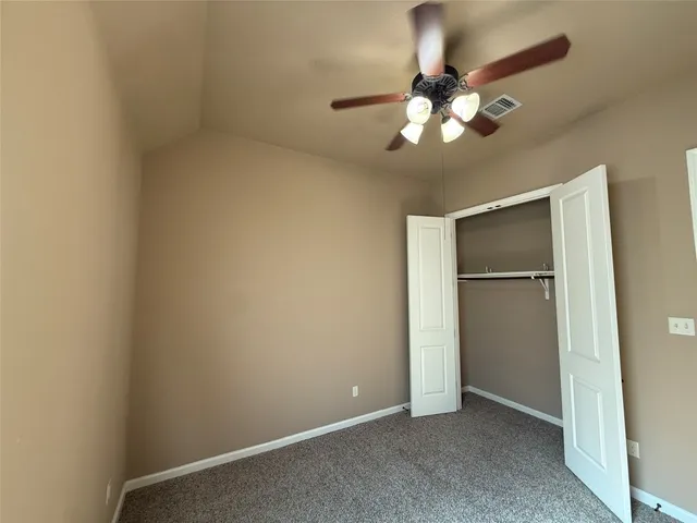 an empty room with a chandelier fan and closet