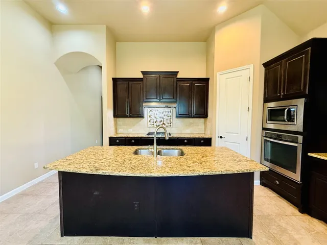 a kitchen with kitchen island granite countertop a sink and refrigerator