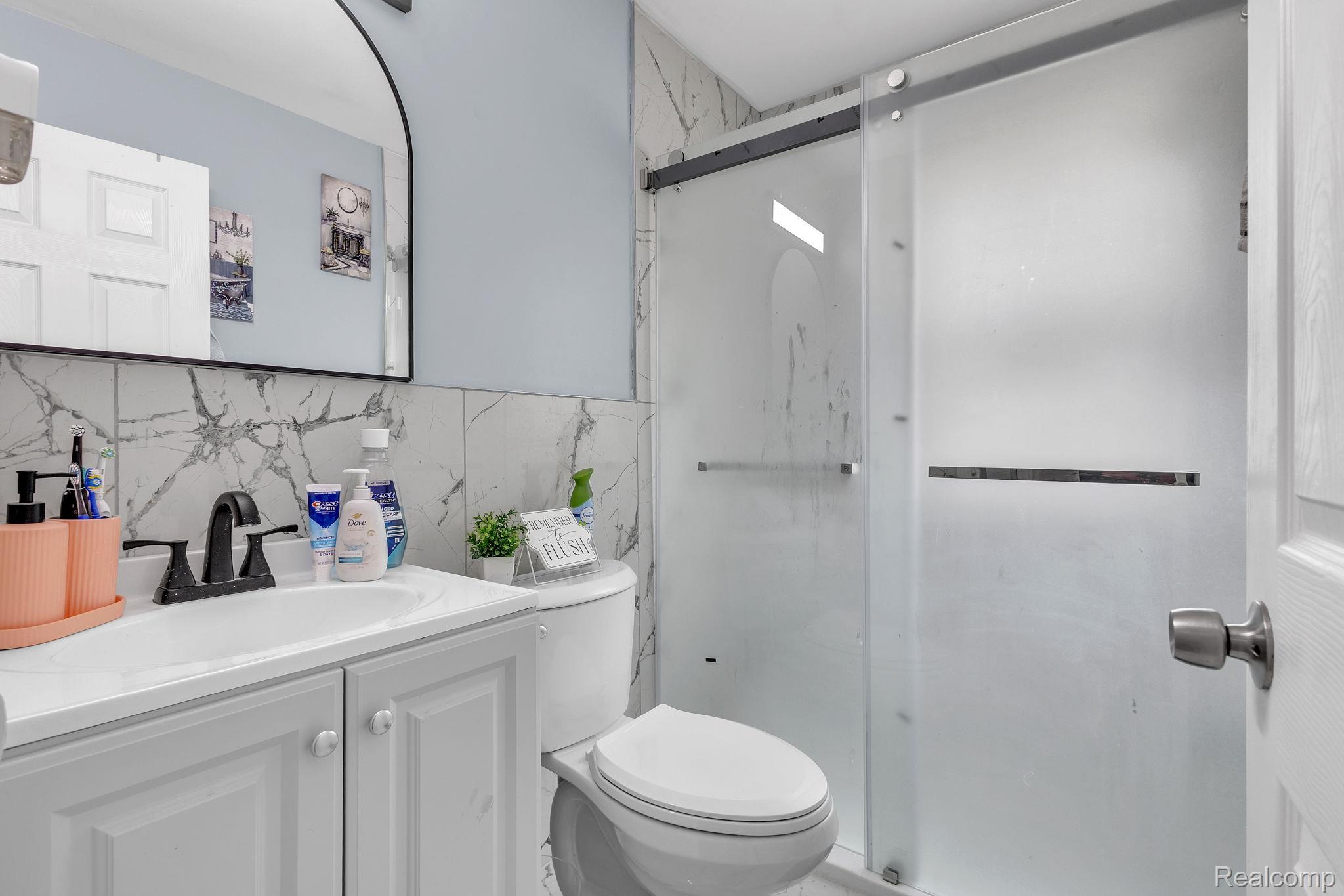 8401 Fielding Street Detroit, MI 48228 - Photo 13 of 34 Bathroom with vanity, a shower stall, and tile walls