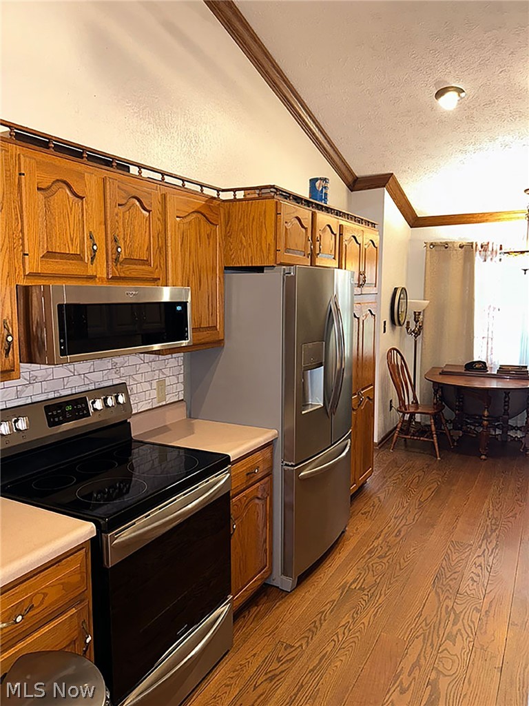 14987 Strader Road East Liverpool, OH 43920 - Photo 11 of 13 Kitchen featuring tasteful backsplash, vaulted ceiling, wood-type flooring, ornamental molding, and appliances with stainless steel finishes