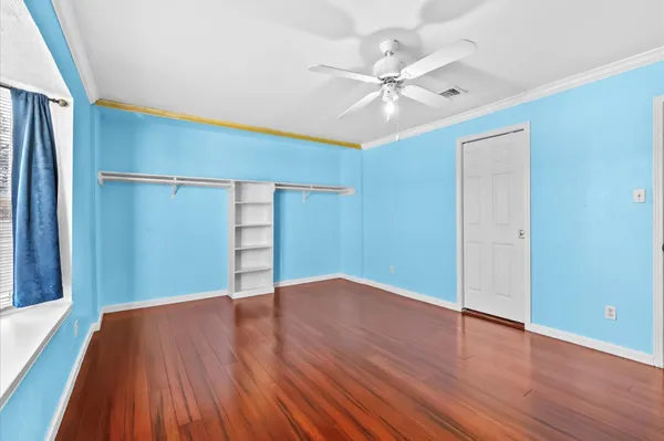 an empty room with wooden floor closet and fan