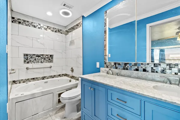 a bathroom with a granite countertop sink a toilet a mirror and shower