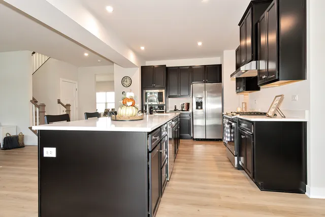 a kitchen with stainless steel appliances kitchen island granite countertop a sink a stove top oven a refrigerator and cabinets