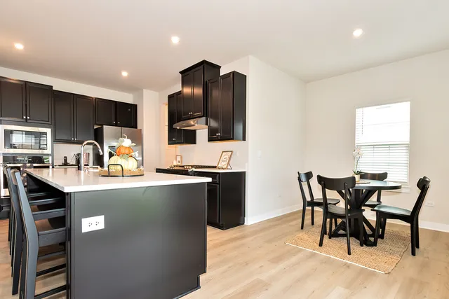 a kitchen with kitchen island granite countertop a dining table chairs and a refrigerator