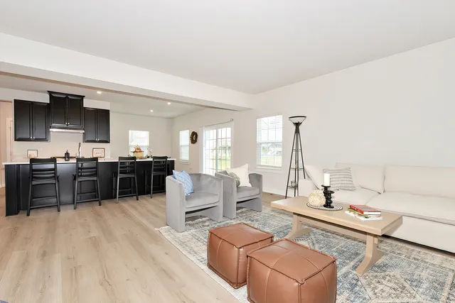 a living room with furniture kitchen view and a large window