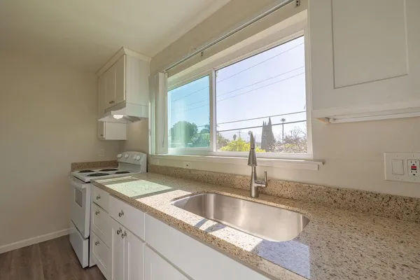 a bathroom with a granite countertop sink and a window
