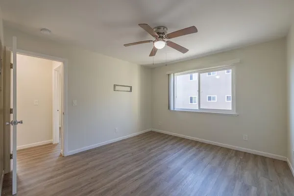 a view of an empty room with wooden floor and a window