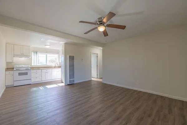 a view of an empty room with wooden floor and a window