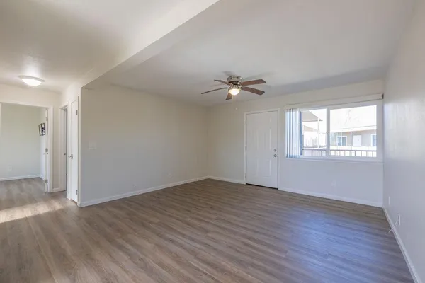 a view of an empty room with wooden floor and a window