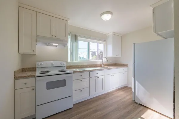 a kitchen with granite countertop white cabinets and white appliances