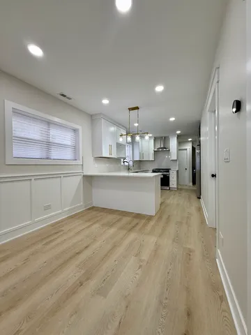 a kitchen with stainless steel appliances granite countertop a refrigerator a sink dishwasher a stove and white cabinets with wooden floor