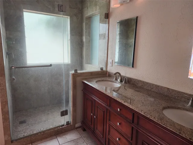 a bathroom with a granite countertop sink a mirror and a shower