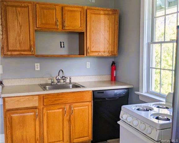 Kitchen with white stove, light countertops, dishwasher, and healthy amount of natural light