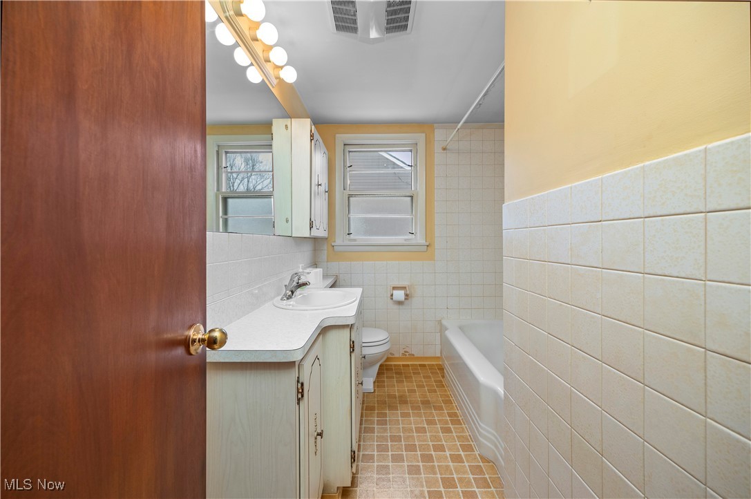 25950 Bagley Road Olmsted Falls, OH 44138 - Photo 18 of 32 Full bath featuring tile walls, vanity, washtub / shower combination, and light tile patterned floors
