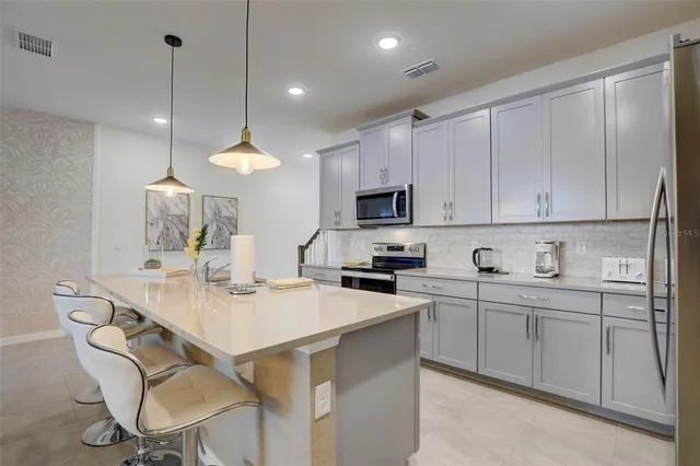 a kitchen with stainless steel appliances kitchen island granite countertop a sink a stove a dining table and chairs