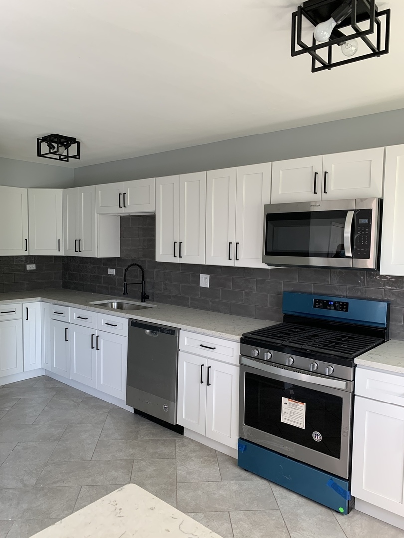 74 West 140th Street Riverdale, IL 60827 - Photo 3 of 20 a kitchen with granite countertop a stove a microwave a sink and cabinets