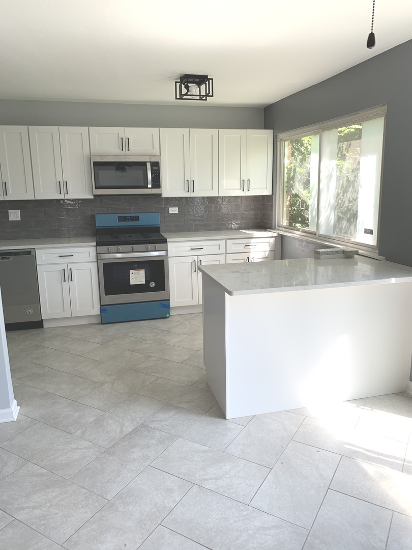 74 West 140th Street Riverdale, IL 60827 - Photo 5 of 20 a kitchen with a sink a stove top oven and white cabinets