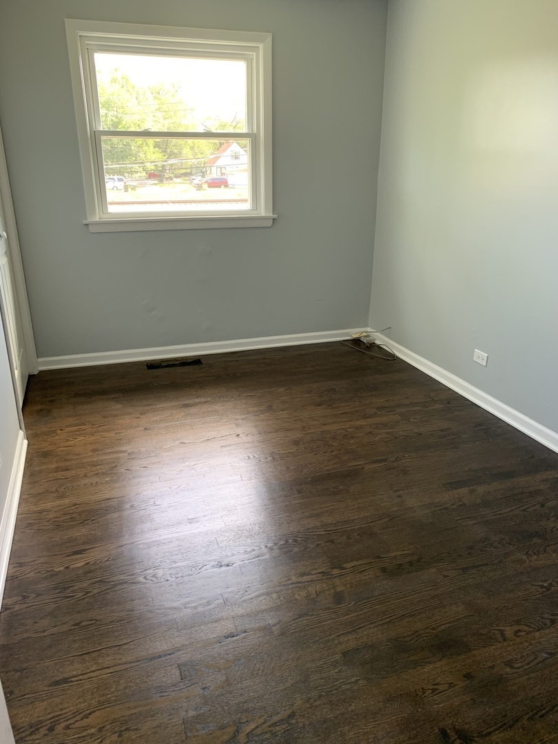 74 West 140th Street Riverdale, IL 60827 - Photo 8 of 20 a view of an empty room with wooden floor and a window
