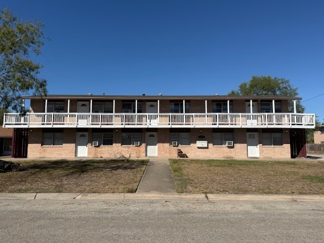 a view of a large white building with glass windows and a small yard