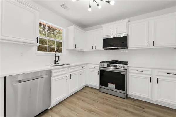 a kitchen with cabinets stainless steel appliances a sink and a window